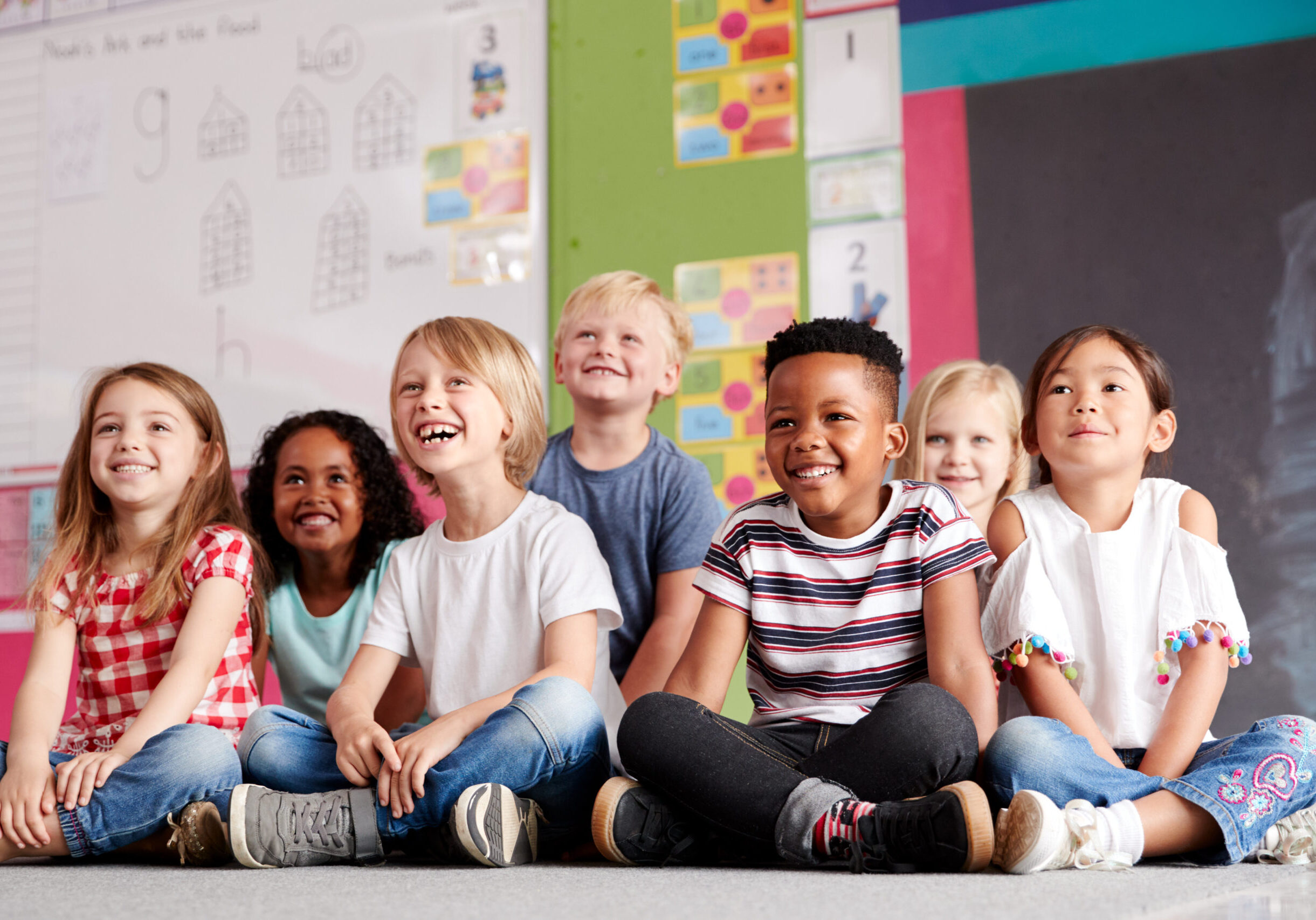 Group Of Elementary School Pupils Sitting On Floor In Classroom